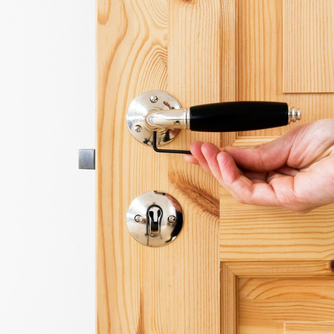 Hånd, der spænder en skruebolt til et klassisk dørgreb.