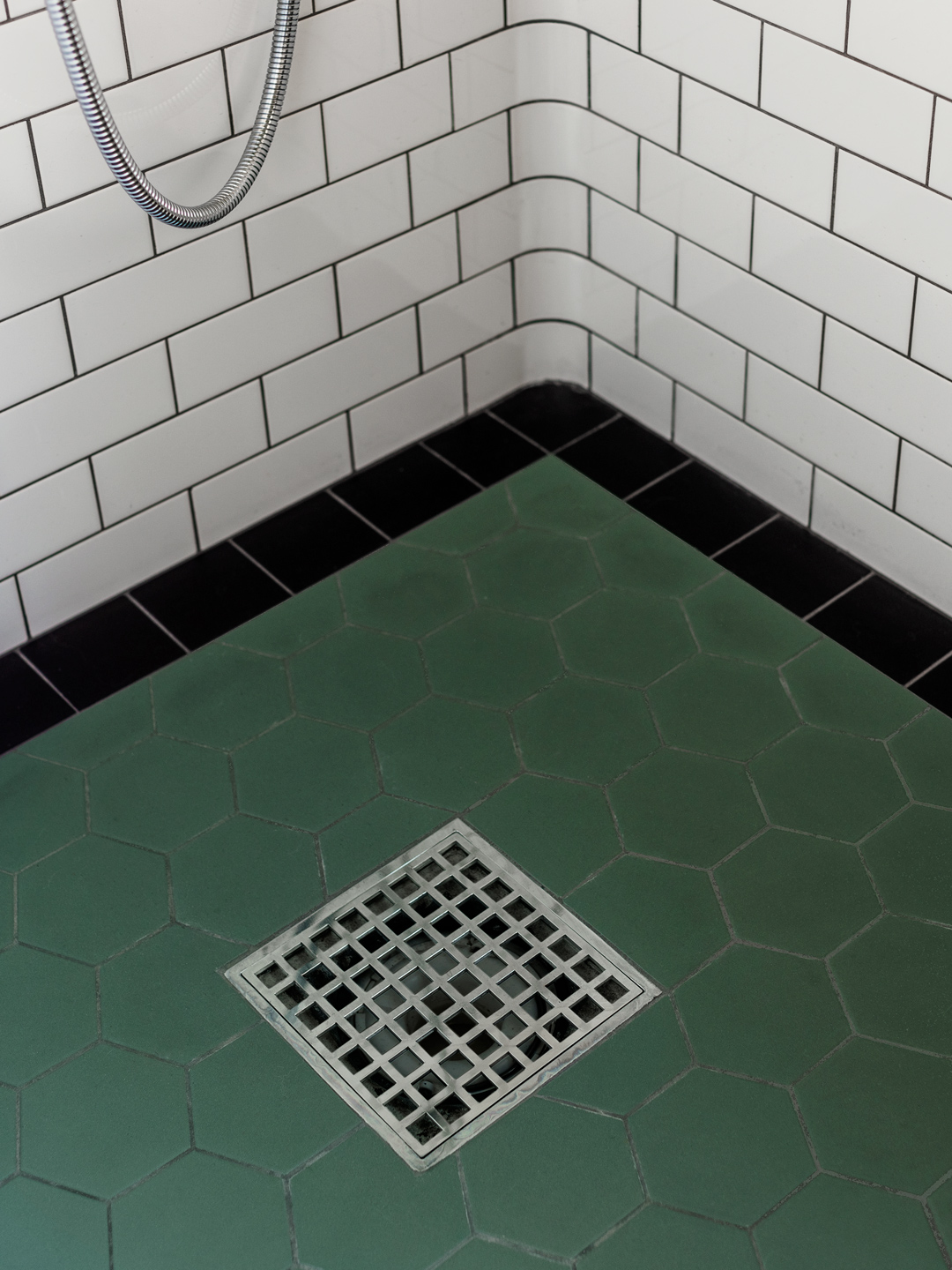 Brusehj&oslash;rne med hvide fliser, sort gulvkant og gr&oslash;nne sekskantede klinker