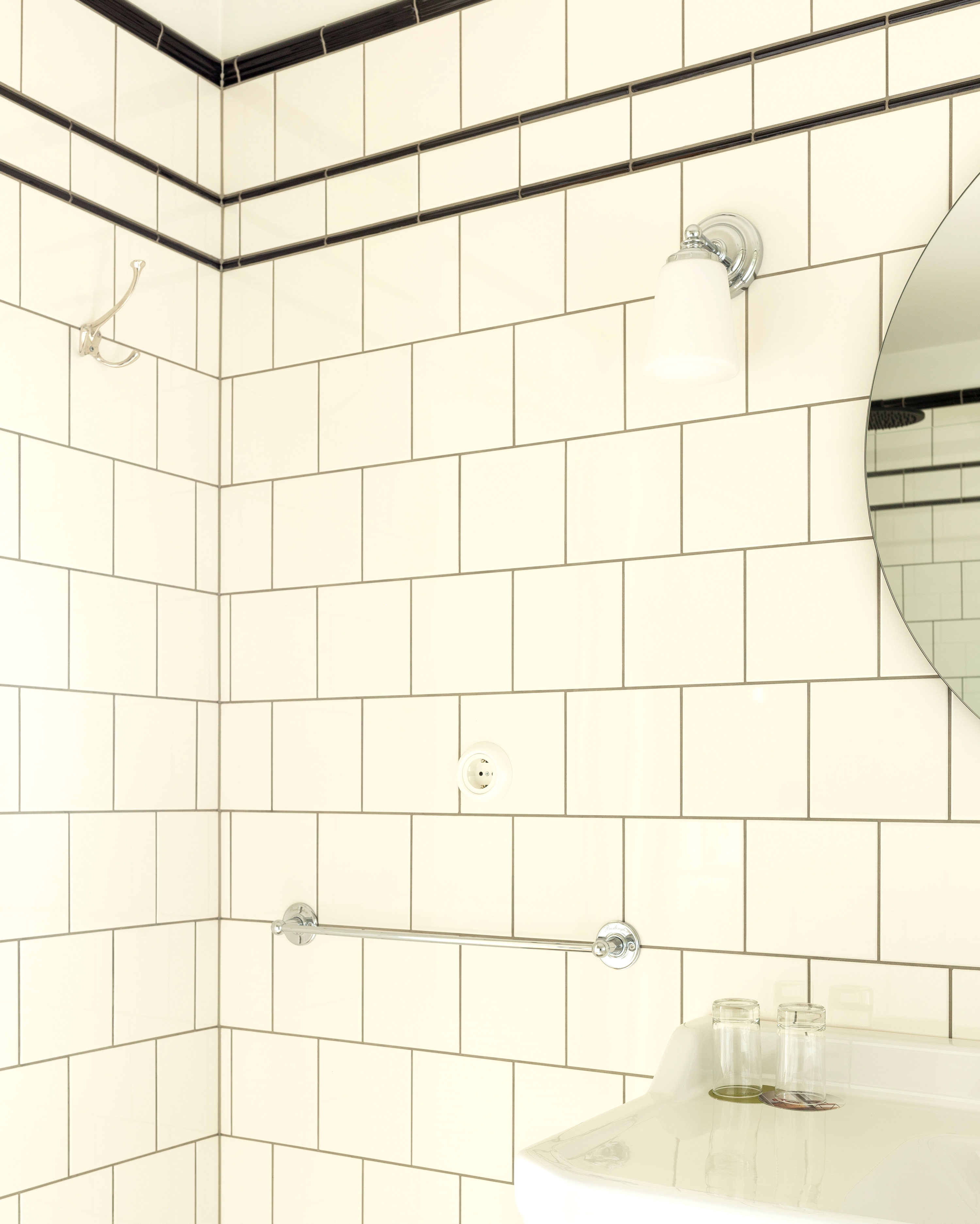 Badev&aelig;relse med hvide fliser p&aring; v&aelig;ggene og sorte fliselister &oslash;verst