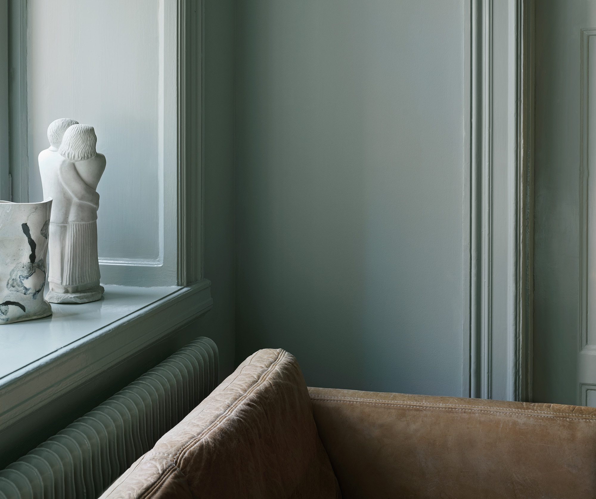 Rum hvor v&aelig;gge, tr&aelig;v&aelig;rk og radiatorer er malet i samme farve Gr&aring;p&auml;ron