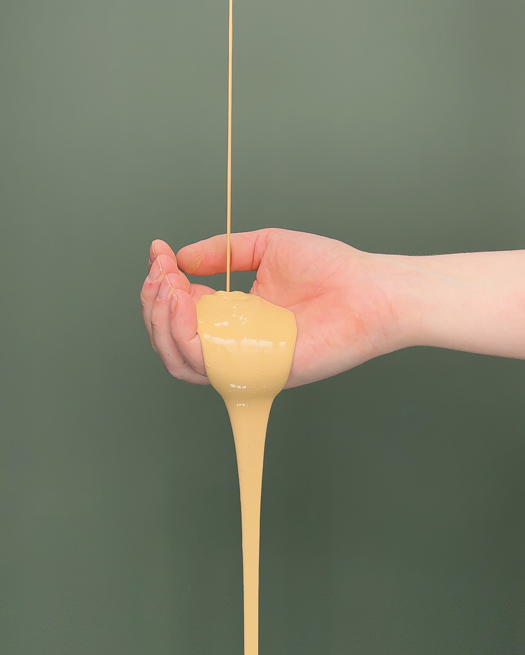 H&aring;nd med gul maling, der h&aelig;ldes ud mod gr&oslash;n baggrund