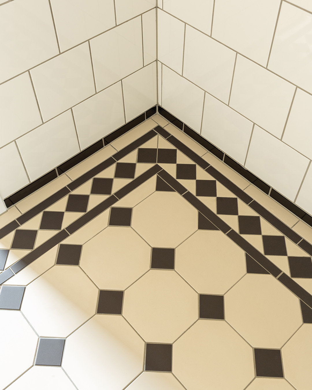 Victorianske gulvfliser i m&oslash;nster York i sort og beige med bort i badev&aelig;relse med hvide v&aelig;gfliser.