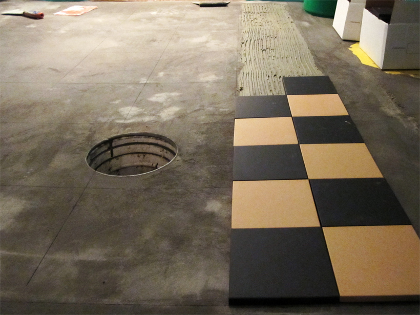 F&oslash;rste r&aelig;kke klinker l&aelig;gges p&aring; gulvet med flisekl&aelig;b.