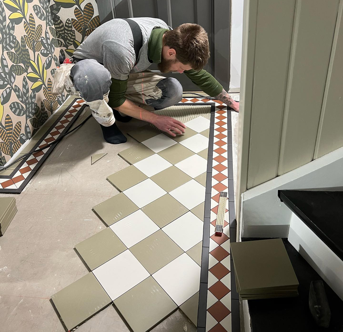 H&aring;ndv&aelig;rker l&aelig;gger victorianske gulvfliser i skakbr&aelig;tm&oslash;nster i en entre