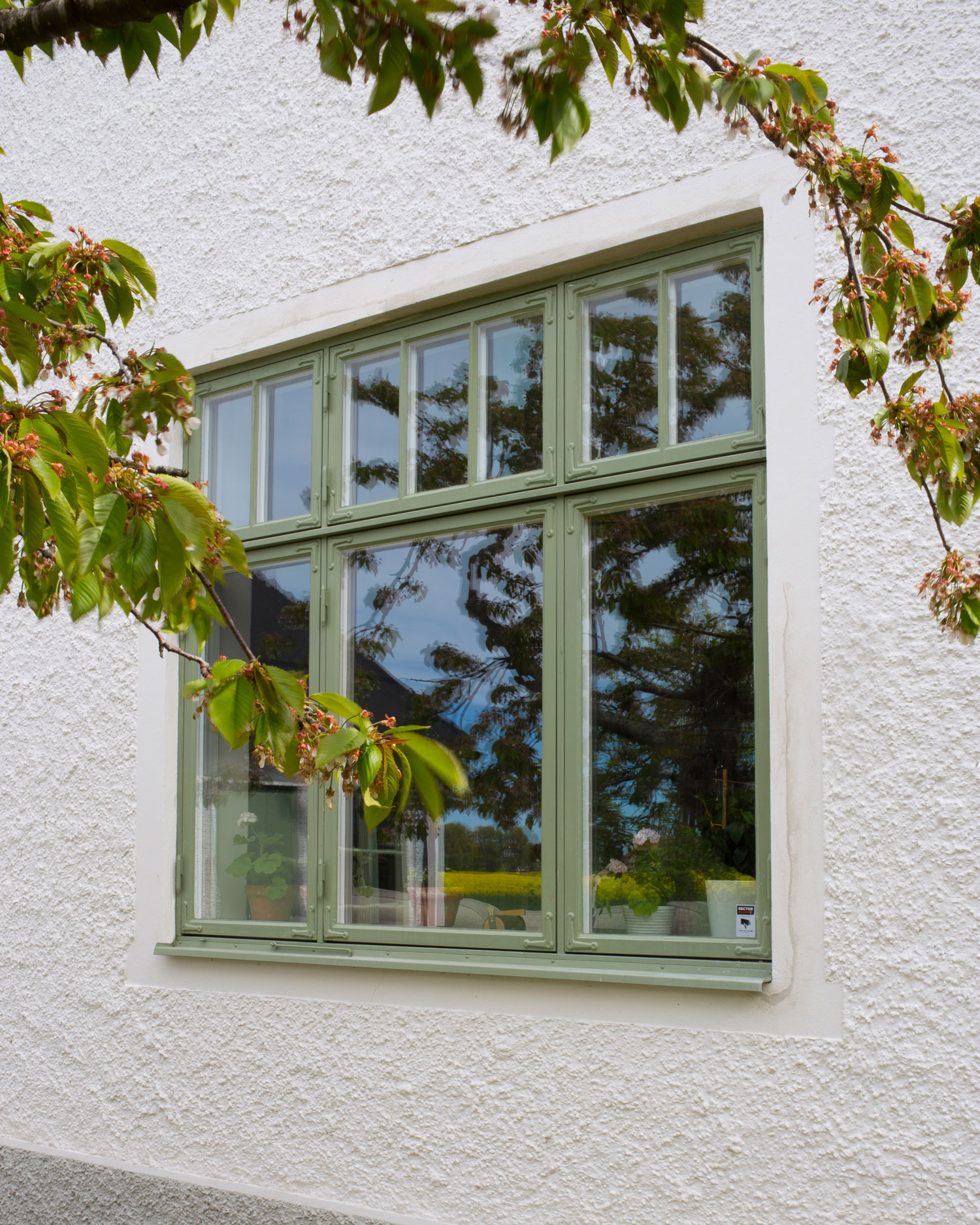 F&ouml;nster m&aring;lad med gr&ouml;n linoljef&auml;rg p&aring; en vit putsad fasad.