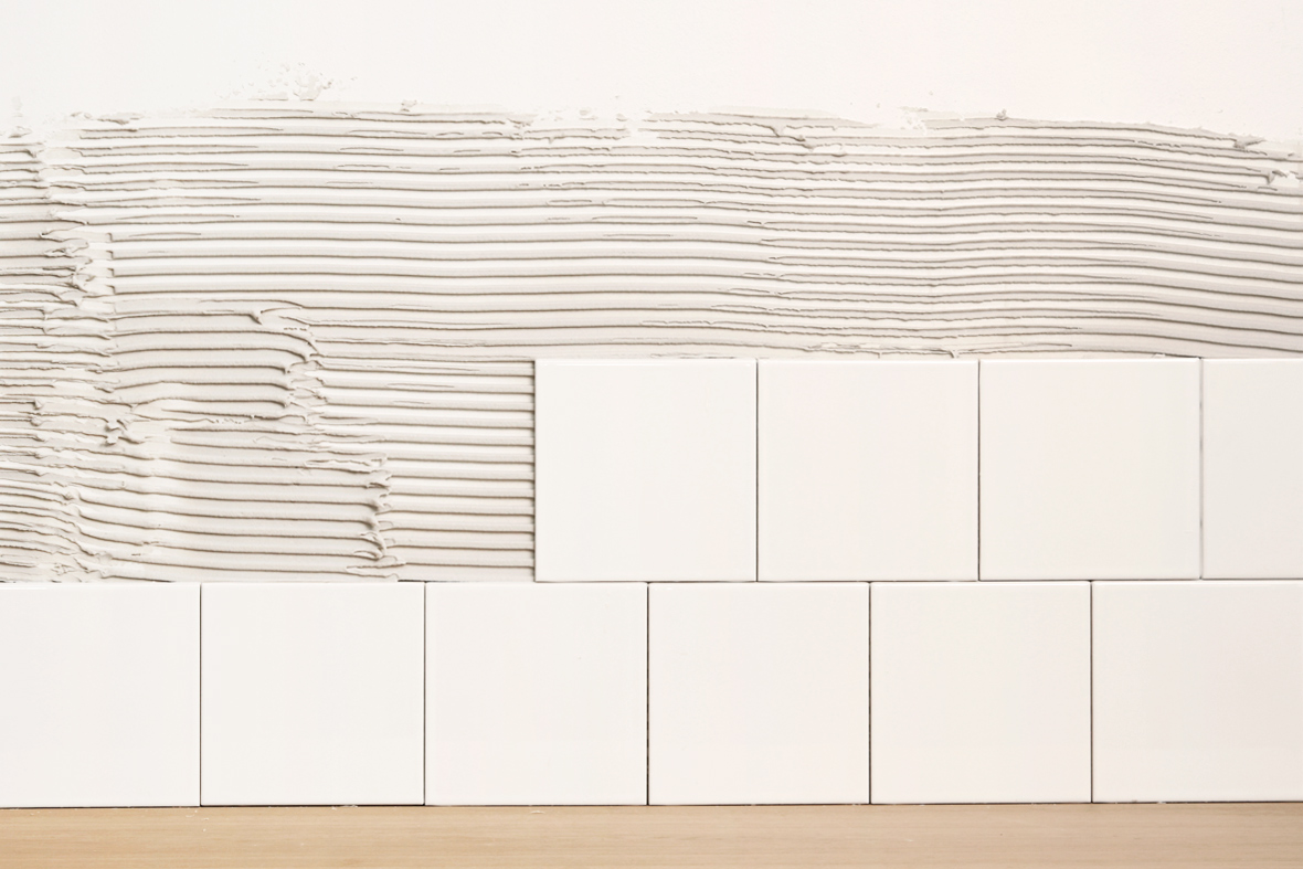 Ops&aelig;tning af anden r&aelig;kke fliser i forbandt p&aring; k&oslash;kkenv&aelig;ggen.